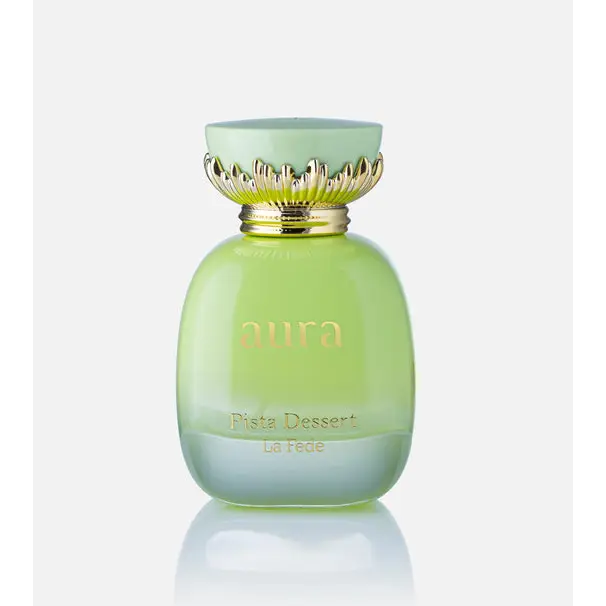 A pale green glass perfume bottle with a gold leaf cap and aura branding for aura pista dessert khadlaj edp 100ml