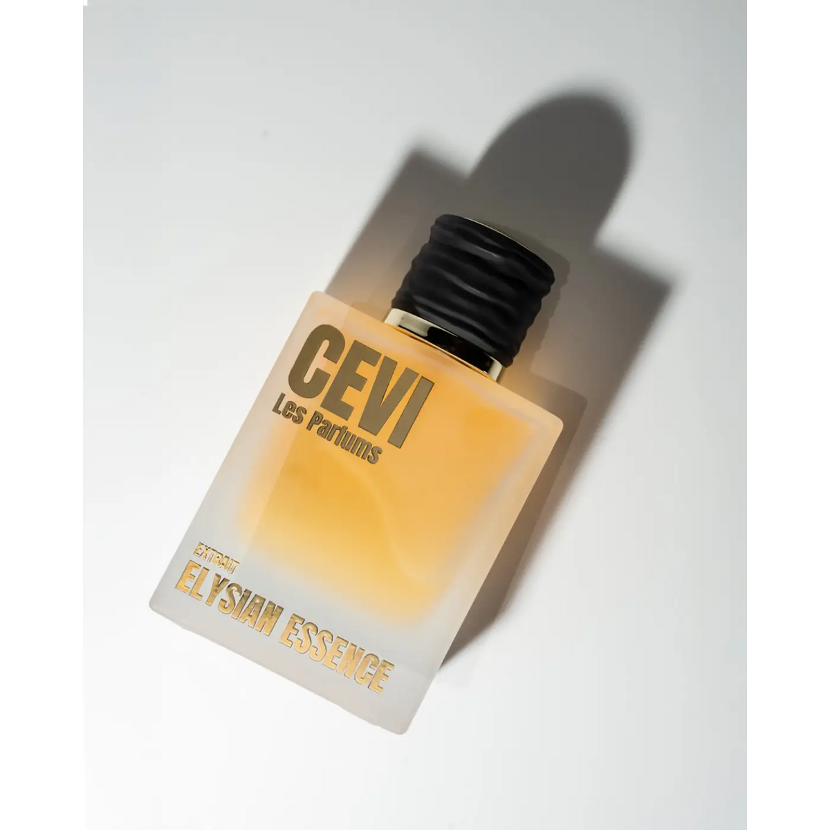 A translucent amber glass bottle of Elysian Essence CEVI EDP 100ml perfume with black ribbed cap and gold lettering