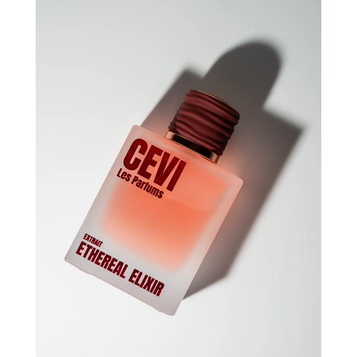 A frosted glass bottle of cevi les parfums ethereal elixir perfume 100ml with a maroon ribbed cap and red lettering